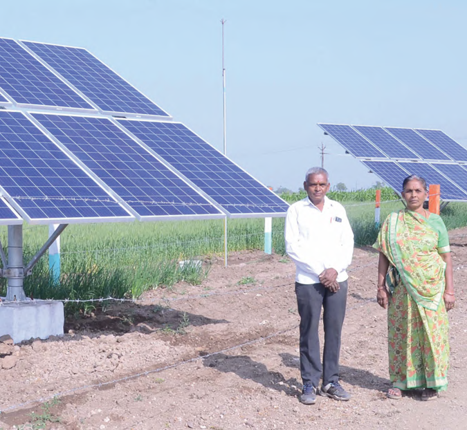Farmers beside a ground-mounted PM-KUSUM solar installation